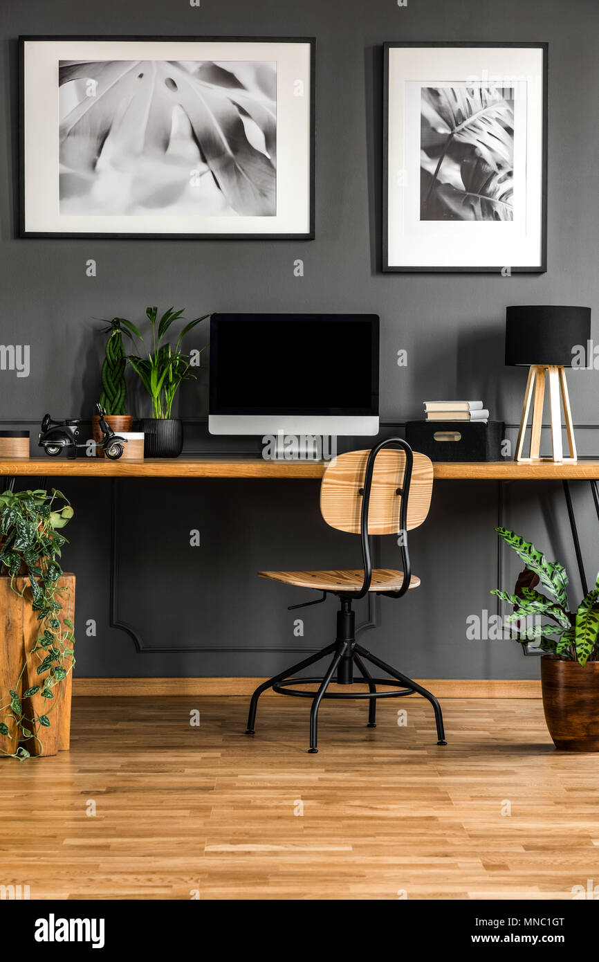 Real Photo von einem dunklen holzernen home office Interieur mit leeren Computermonitor o der Schreibtisch stehend gegen schwarze Wand mit Spritzguss Stockfotografie Alamy