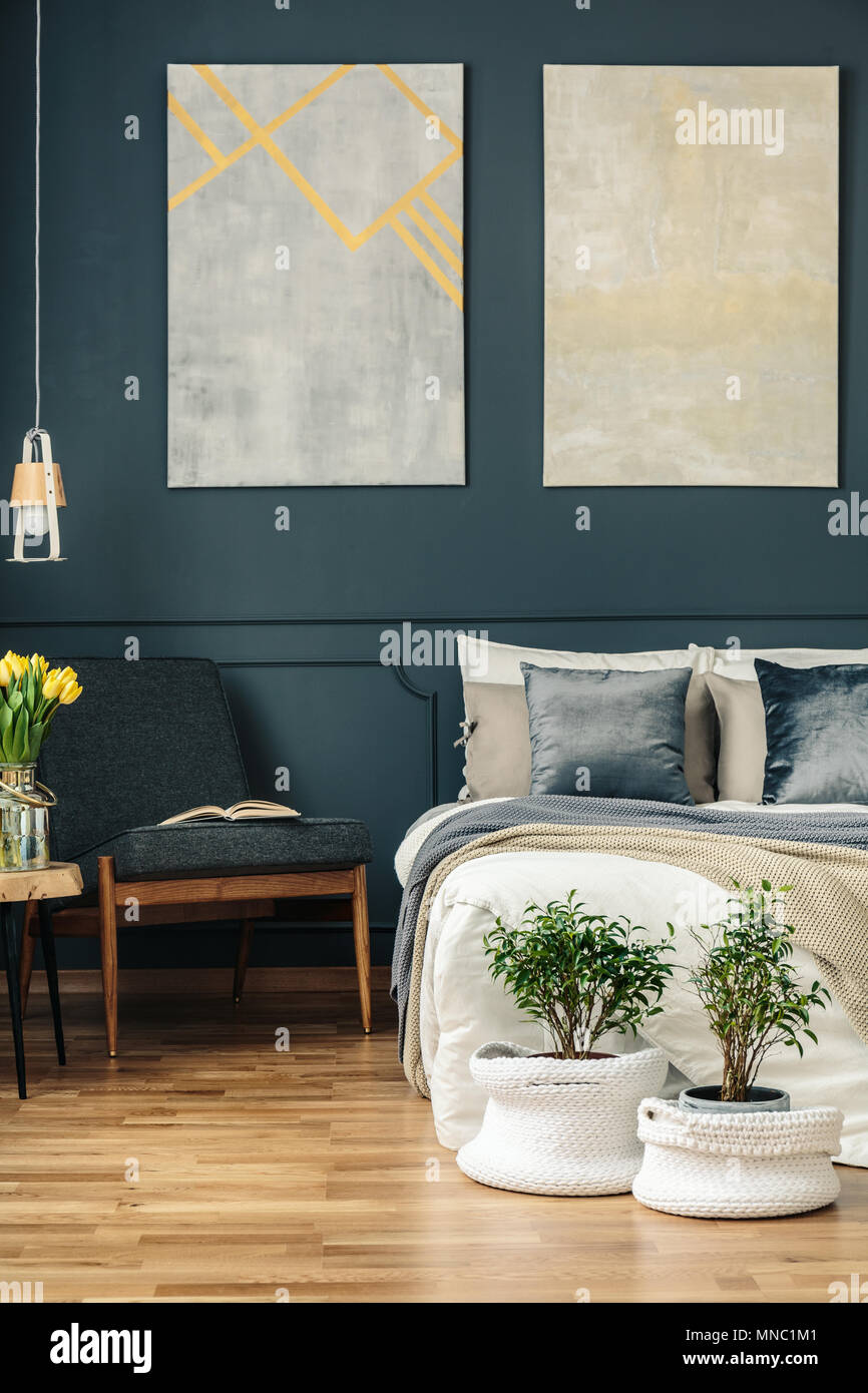 Vintage Schlafzimmer Innenraum mit Sessel, Bett, Blumen, Pflanzen und Gemälde an der Wand Stockfoto