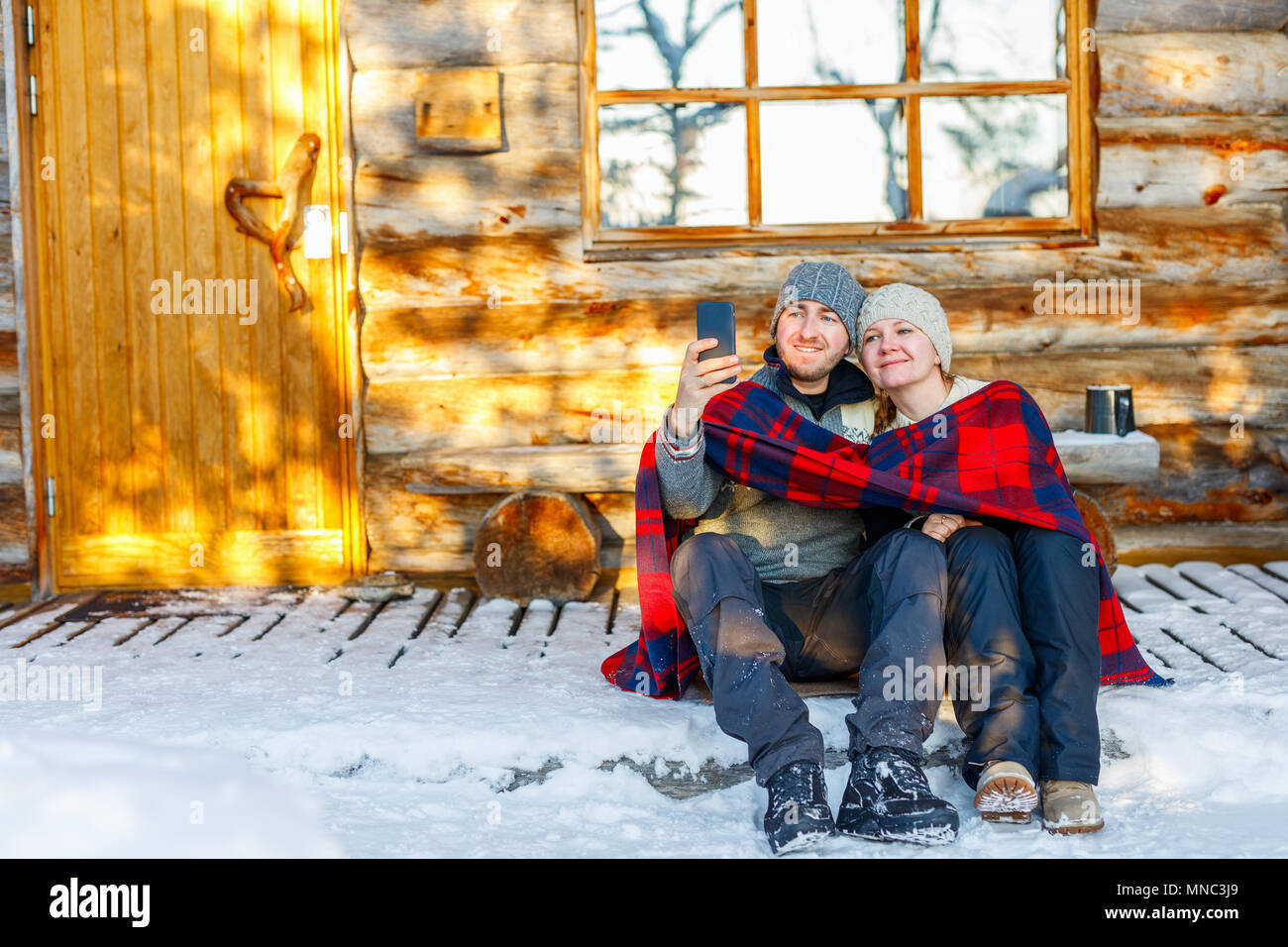 Paar im Freien auf der schönen Wintertag vor der Hütte Ferienhaus anmelden Stockfoto