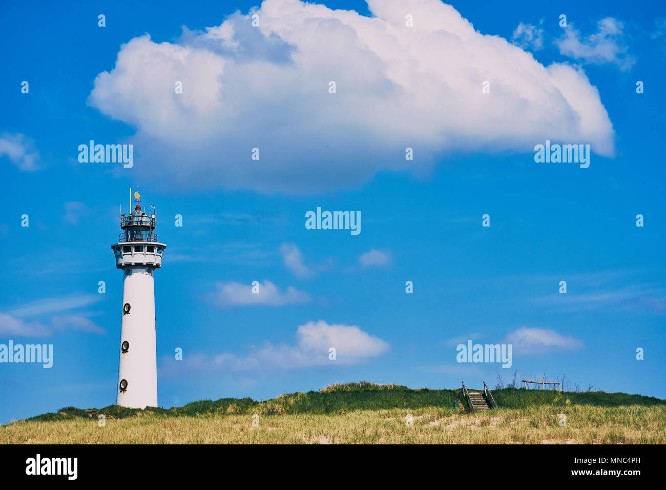 Weißen Leuchtturm in Egmond aan Zee in den Niederlanden mit blauem Himmel und einem großen weißen Wolke Stockfoto