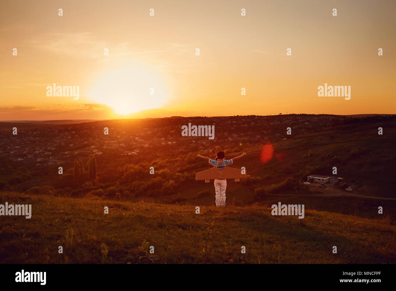 Junge spielt mit einem Flugzeug über die Natur bei Sonnenuntergang. Stockfoto