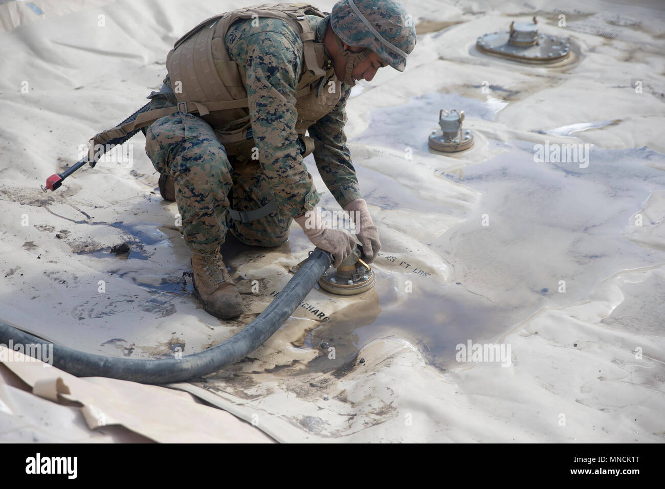 Us Marine Lance Cpl. Carlos Effio, bilk Kraftstoff Spezialist mit 7. Techniker Bataillon, 1. Marine Logistik Gruppe, legt eine Saugleitung auf einem 3.000 Liter Kraftstoff Beutel in Camp Pendleton, Kalifornien, USA, 17. März 2018. Die Saugleitung ist speziell mit Metallhalterung im Schlauch die Leitung zusammenbricht während des Gebrauchs zu verhindern. (U.S. Marine Corps Stockfoto