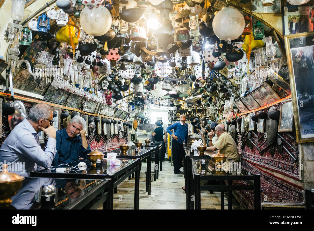 Isfahan, Iran - Oktober 15, 2017: Männer sitzen und Tee an der Azadegan Teehaus, die berühmt für ihre riesige Sammlung von Bric-a-brac hängen von der Decke. Stockfoto