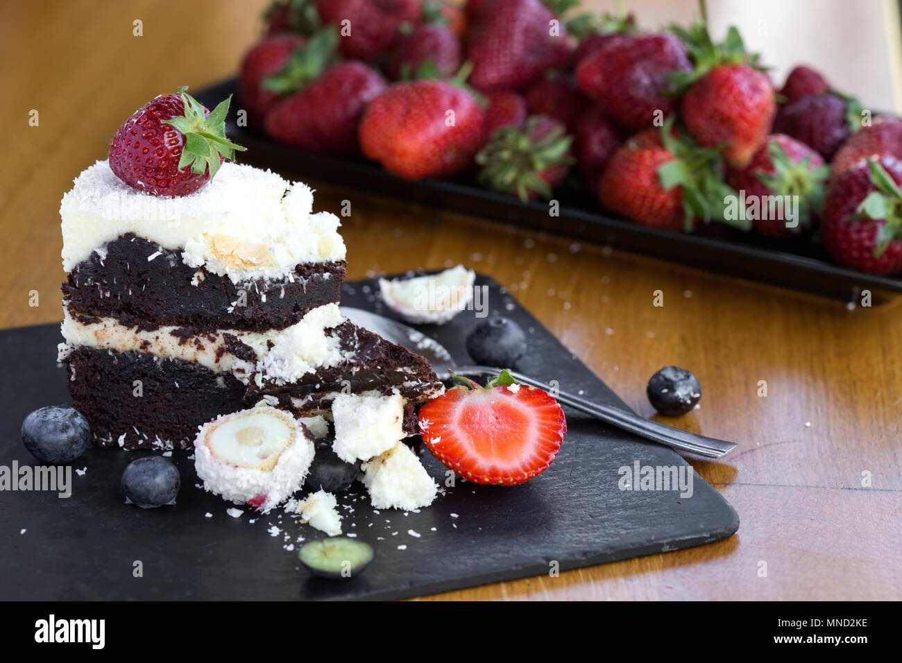 Essen leckere Schokolade Kuchen mit weißer und dunkler Schokolade, Früchte und Kokosnuss auf Schiefer Stockfoto