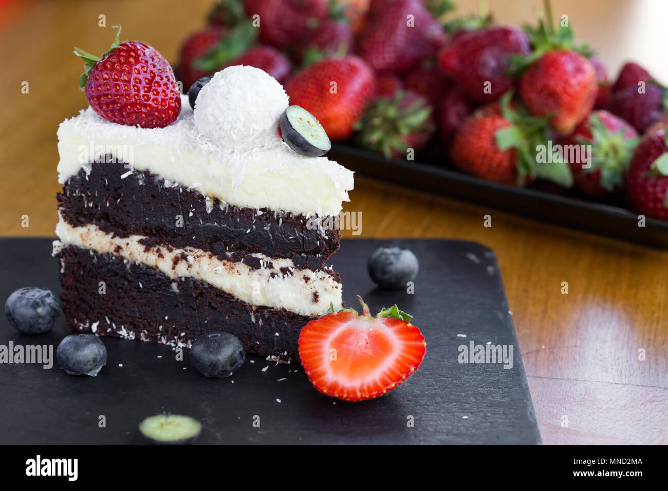Leckere Schokolade Kuchen mit weißer und dunkler Schokolade, Früchte und Kokosnuss auf Schiefer Stockfoto