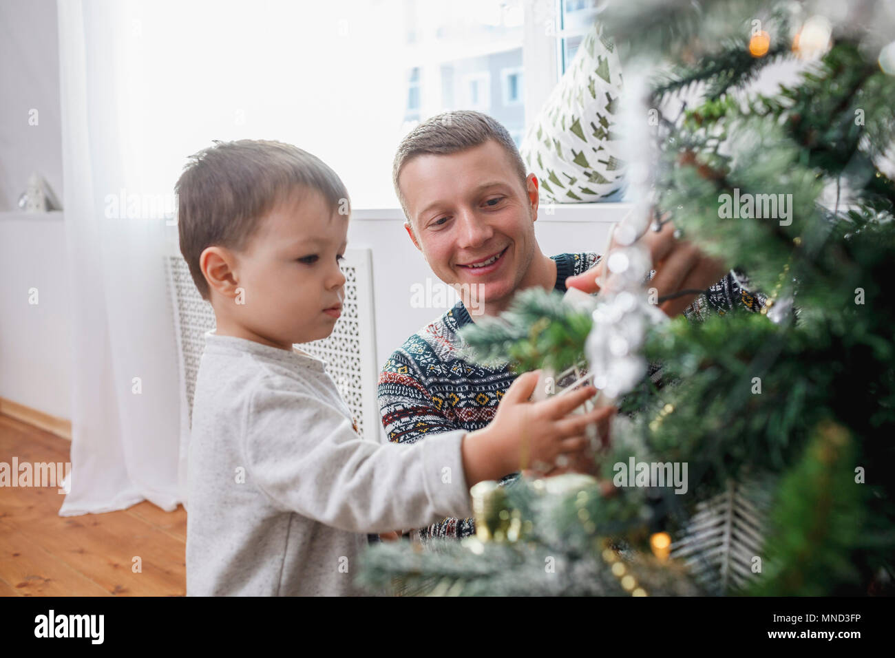 Gerne Vater und Sohn schmücken Weihnachtsbaum zu Hause Stockfoto
