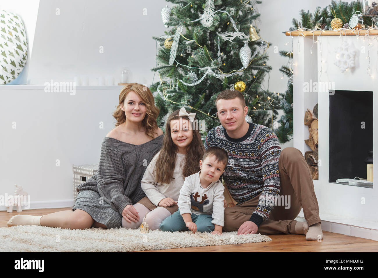 Portrait der glücklichen Familie sitzt gegen Weihnachtsbaum Stockfoto