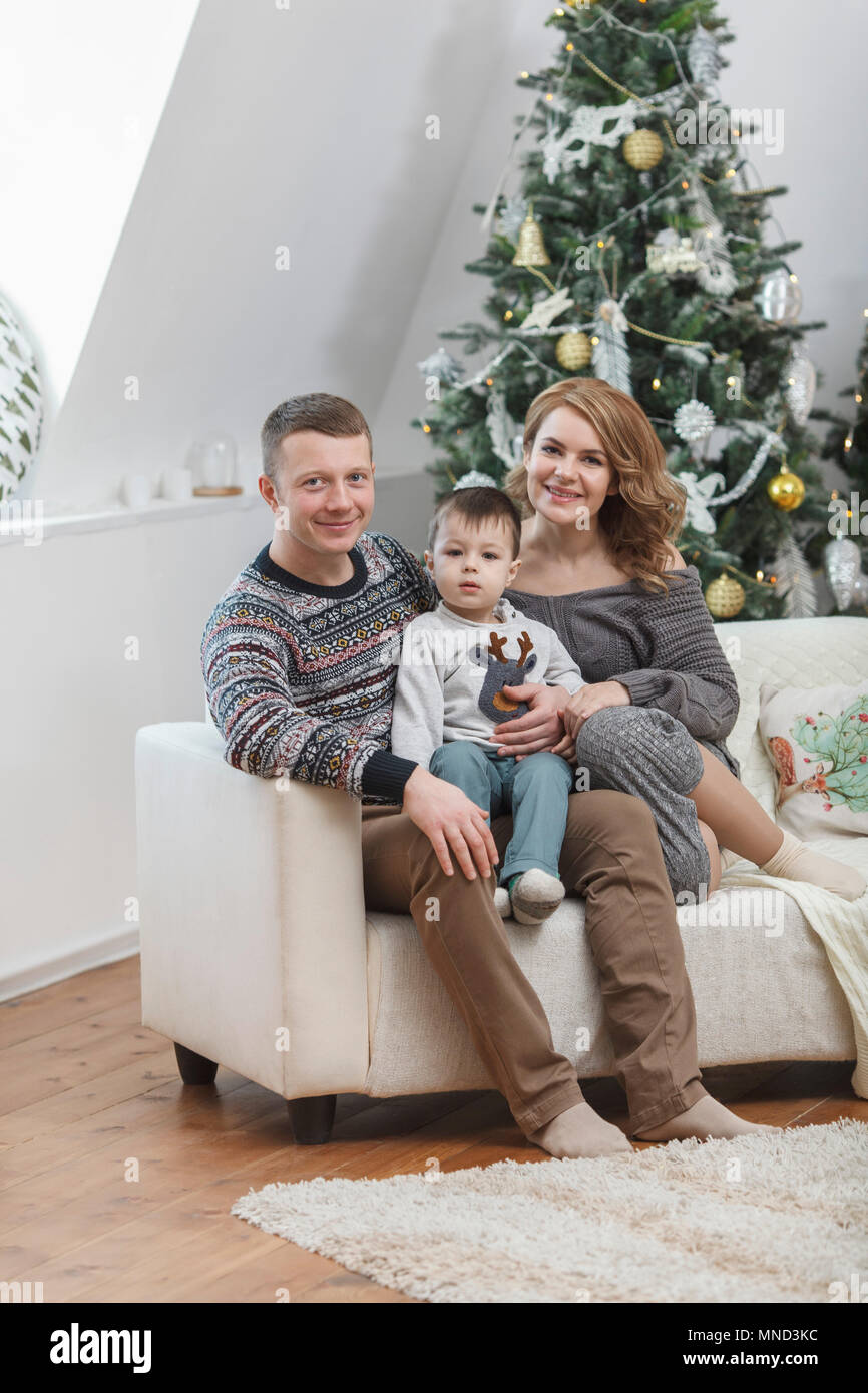 Portrait von lächelnden Mutter und Vater mit Sohn auf dem Sofa gegen Weihnachtsbaum zu Hause Stockfoto