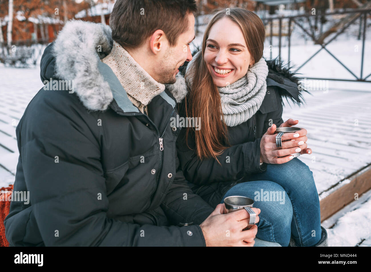 Glückliches Paar sitzen mit Getränke auf der Promenade im Winter Stockfoto