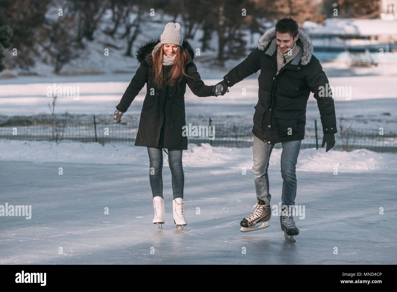 Volle Länge des Menschen Hand in Hand mit Frau, während sie Eislaufen auf der Eisbahn Stockfoto