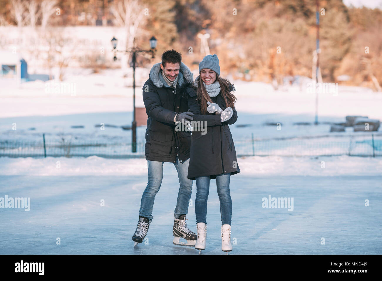 Volle Länge des fröhlichen Paar beim Schlittschuhlaufen auf der Eisbahn Stockfoto