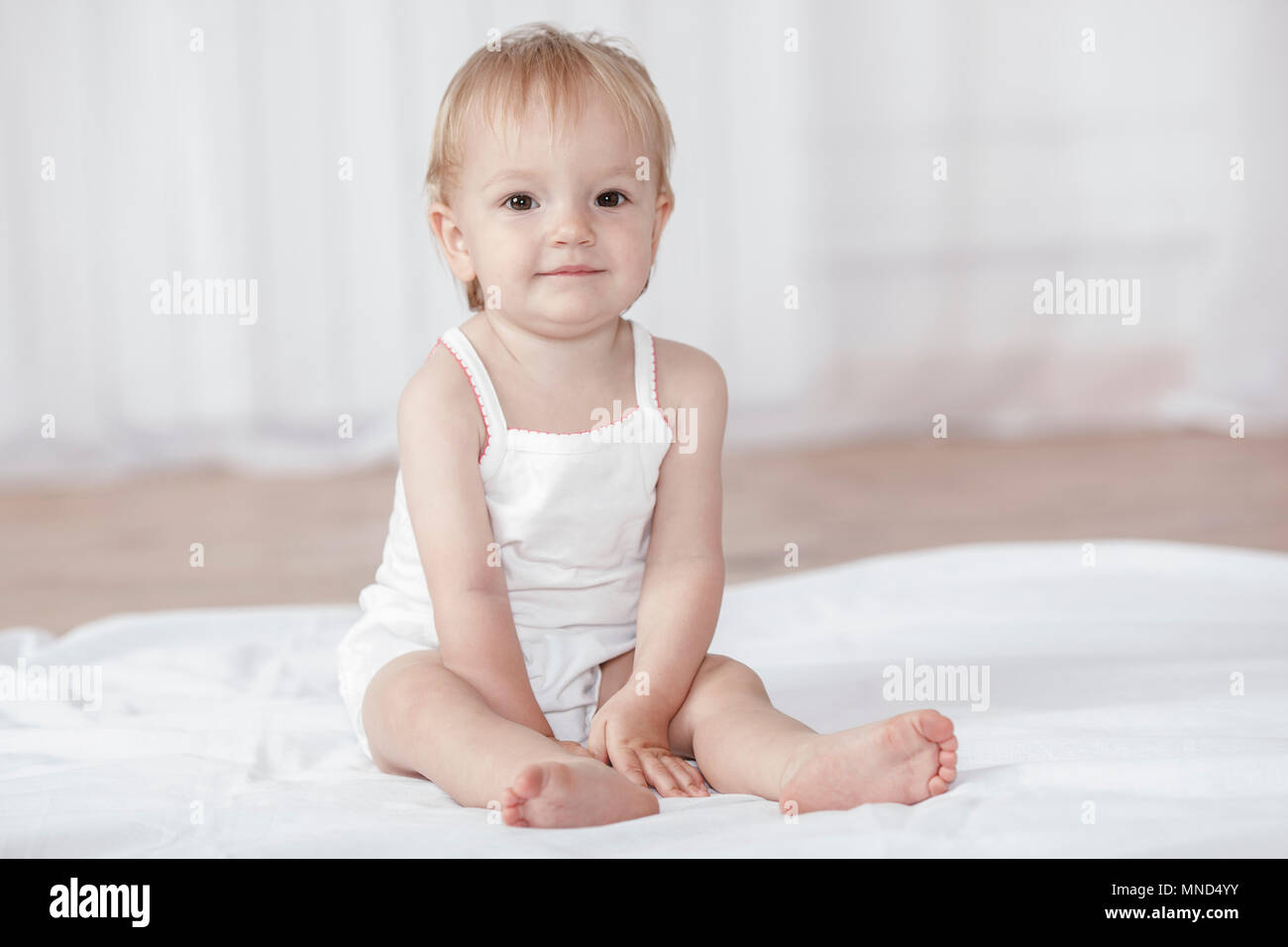 Portrait von niedlichen Baby Mädchen sitzen auf dem Bett zu Hause. Stockfoto