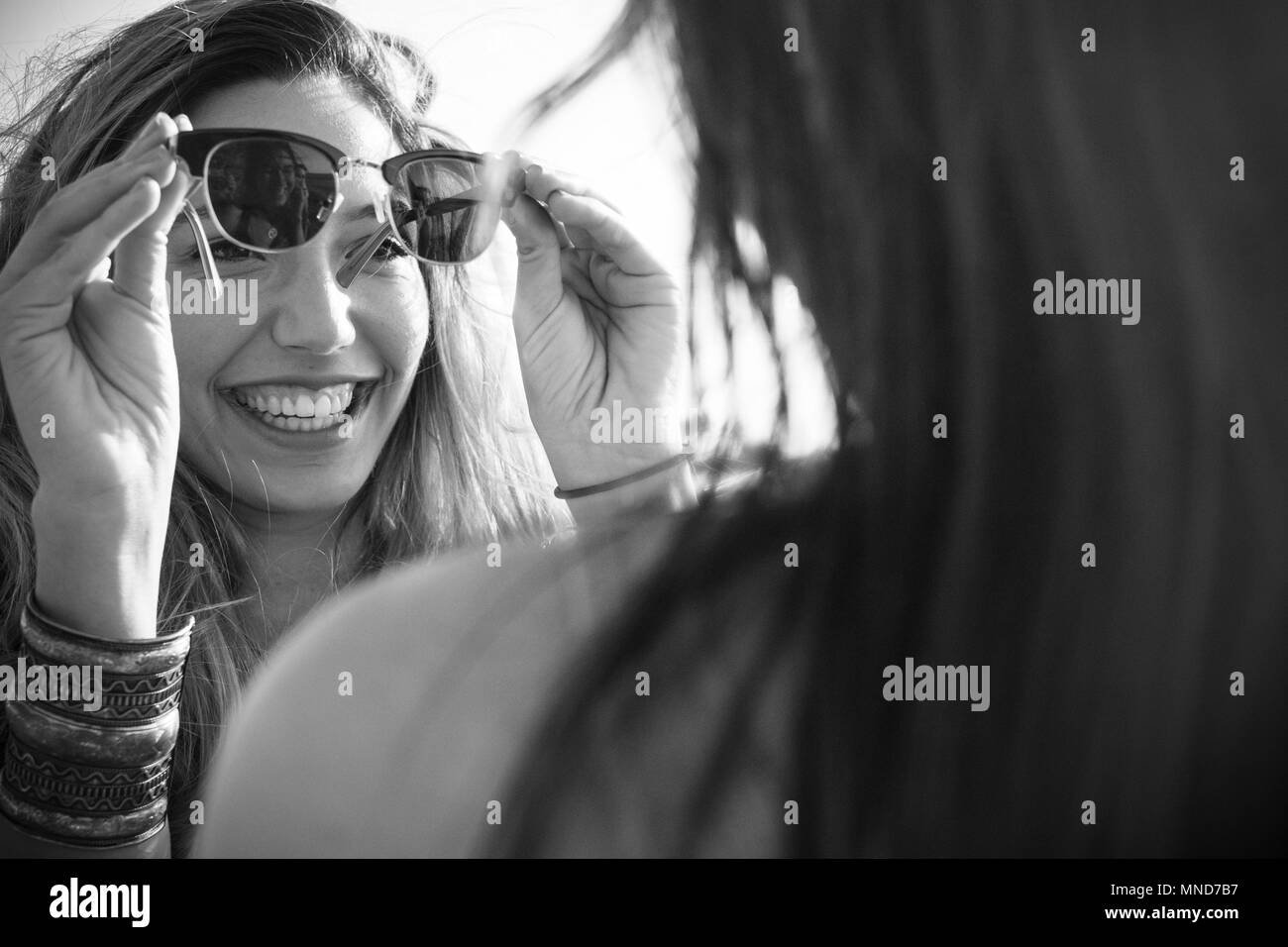 Zwei junge schöne Frau sehen sich mit Brillen in einem sonnigen Tag. Nettes lächeln gesehen von der Rückseite einer Frau. Freundschaft zwischen zwei spanischen Stockfoto