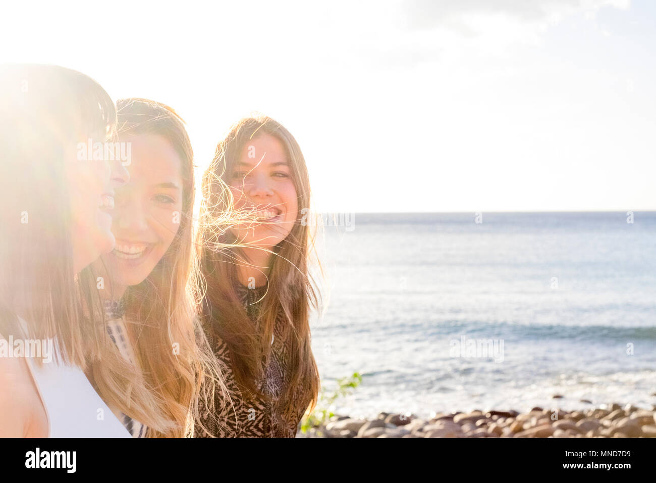 Drei junge Frauen, die Freunde gehen gemeinsam an einer Wand in der Nähe der Strand auf Teneriffa. Die Ferienhäuser unter einem blauen Himmel mit gelben Sonne genießen. Hände von den Händen. Stockfoto Drei junge Frauen, die Freunde gehen gemeinsam an einer Wand in der Nähe der Strand auf Teneriffa. Die Ferienhäuser unter einem blauen Himmel mit gelben Sonne genießen. Hände von den Händen. Stockfoto