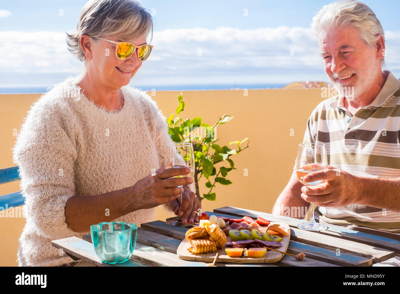 Im Alter Mann und Frau trinkt Wein und Speise leben Früchte und Salami auf der Dachterrasse mit Blick auf den Ozean. Ferienhäuser und pensionierte Konzept für Wunder Stockfoto Im Alter Mann und Frau trinkt Wein und Speise leben Früchte und Salami auf der Dachterrasse mit Blick auf den Ozean. Ferienhäuser und pensionierte Konzept für Wunder Stockfoto