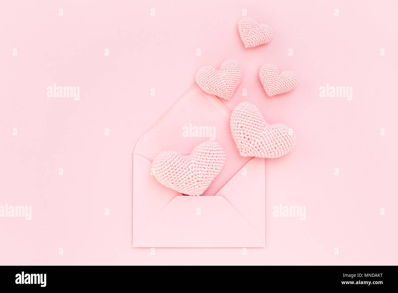 Rosa gestricken Herzen im Umschlag auf rosa Hintergrund. Romantische Gratulation am Valentinstag. Handarbeit, Liebe Beichte. Flach, minimale Urlaub Stockfoto