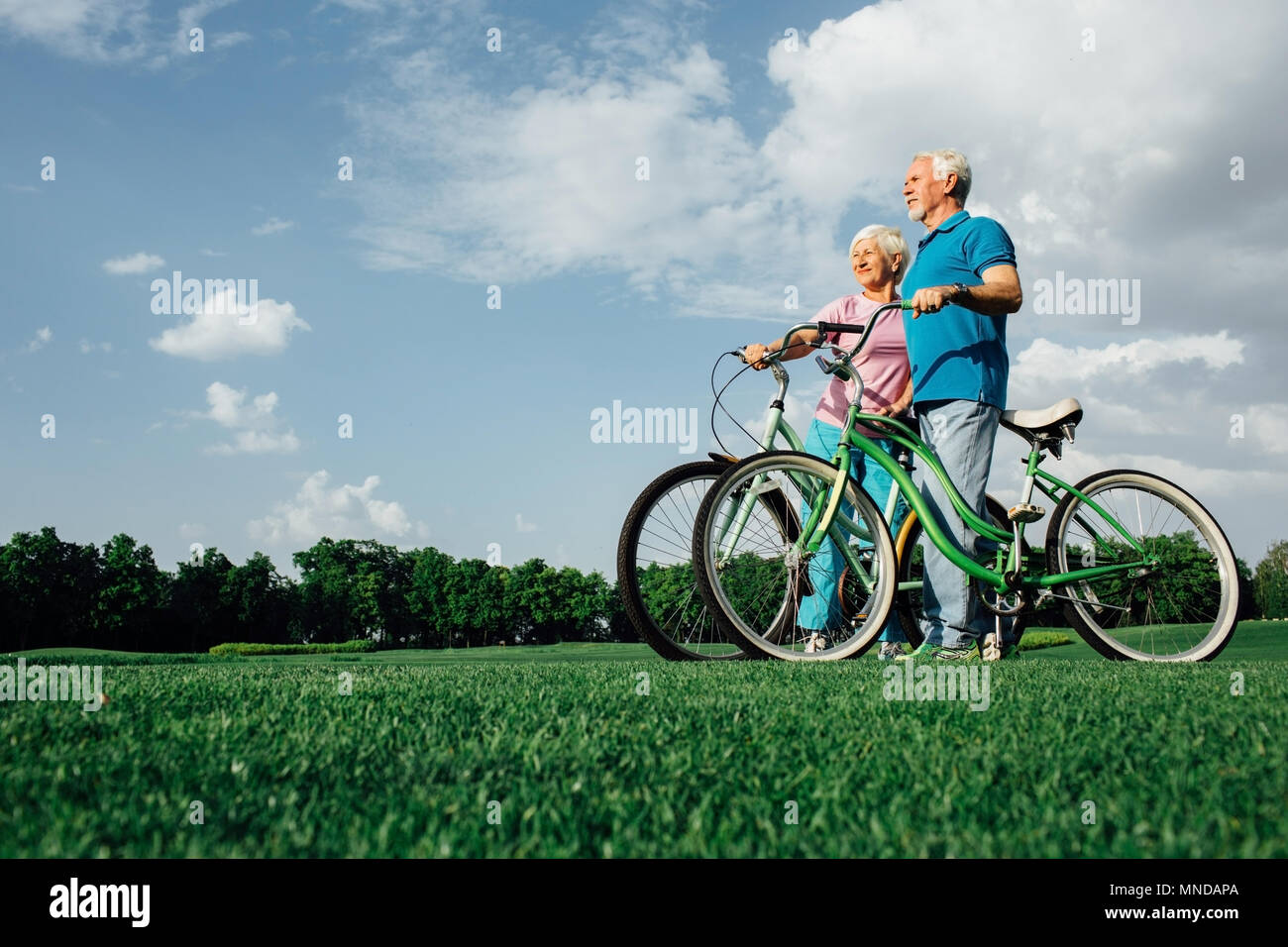 Senior Paar mit ihren Bikes in Park, Seitenansicht Stockfoto