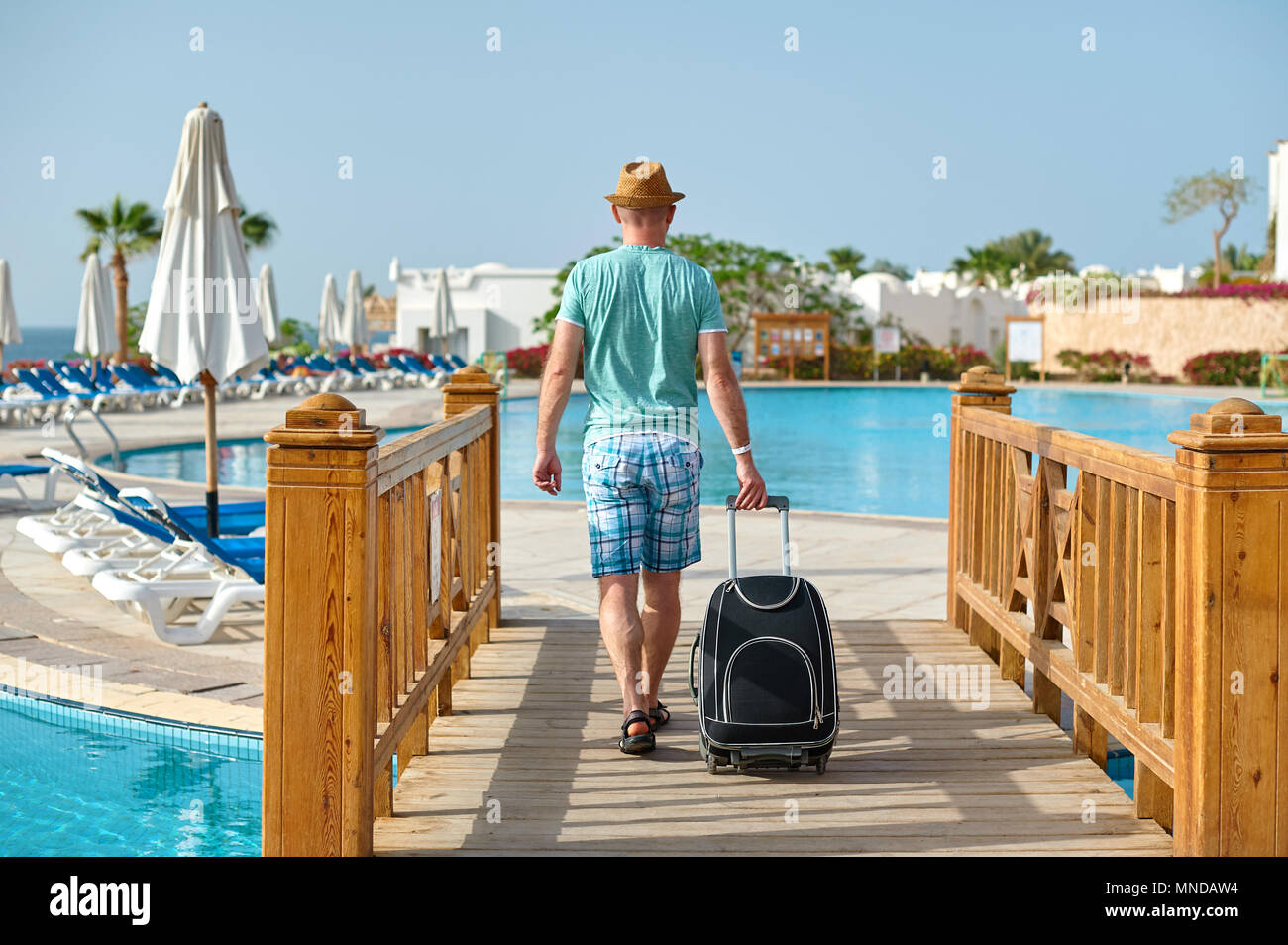 Man Touristen im Sommer Kleidung mit einem Koffer in der Hand, am Meer am Strand suchen, pool im hotel, Vorstellung von Zeit zu reisen Stockfoto