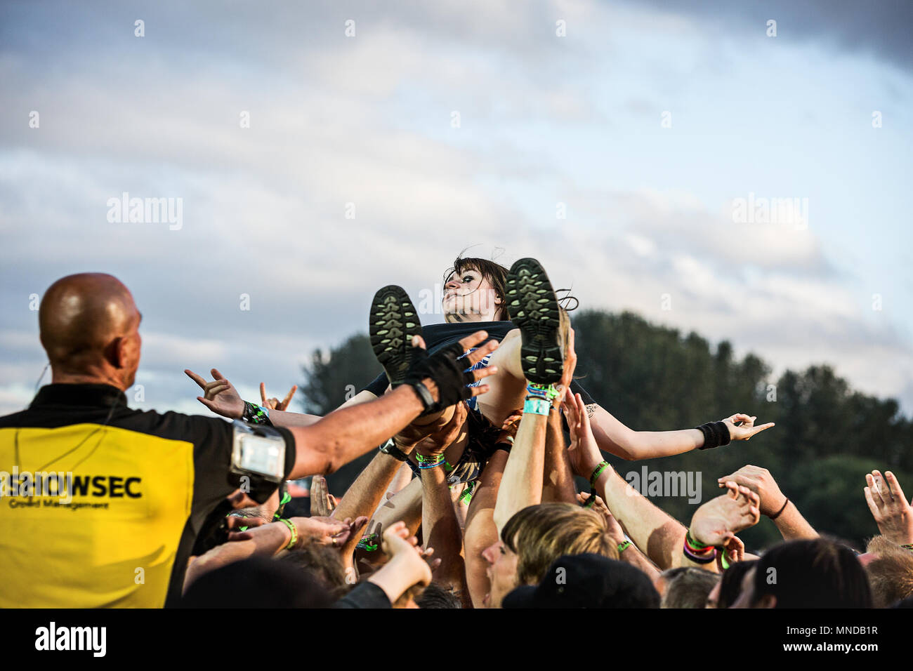 Mädchen crowd Surfer abgehoben über dem Musikfestival Menge, als Sicherheit die man Uhren auf. Stockfoto