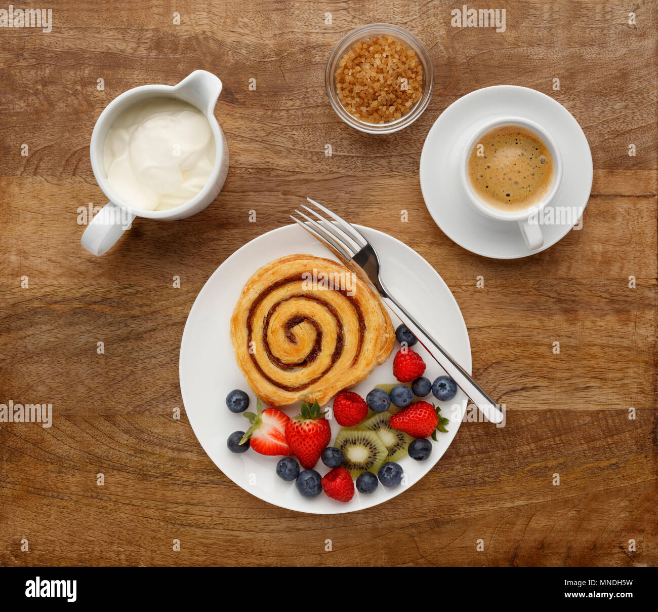 Ein gesundes Frühstück mit einem Cinnamon Swirl, Obst und Kaffee, Schuß auf einer hölzernen Hintergrund, von oben. Stockfoto