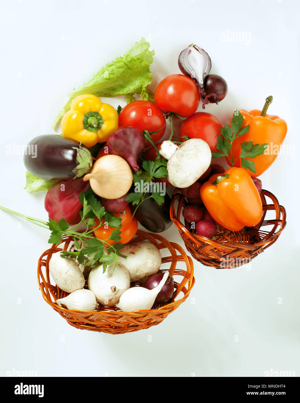Pilze und eine Vielzahl von frischem Gemüse in einem Weidenkorb. isoliert auf einem weißen Stockfoto