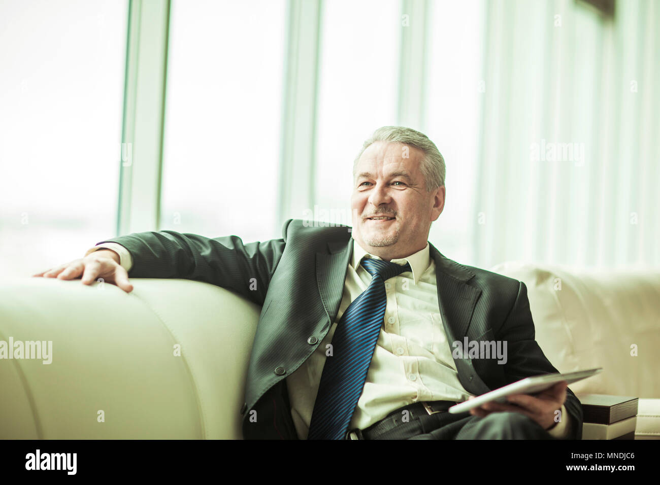 Erfahrenen Rechtsanwalt mit digitalen Tablet auf dem Sofa sitzen im eigenen Büro Stockfoto