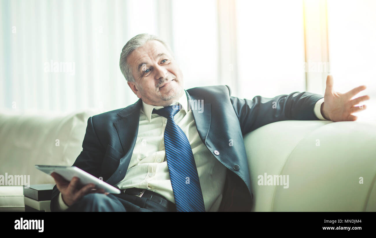 Erfolgreicher Geschäftsmann mit digitalen Tablet auf dem Sofa sitzen im eigenen Büro Stockfoto