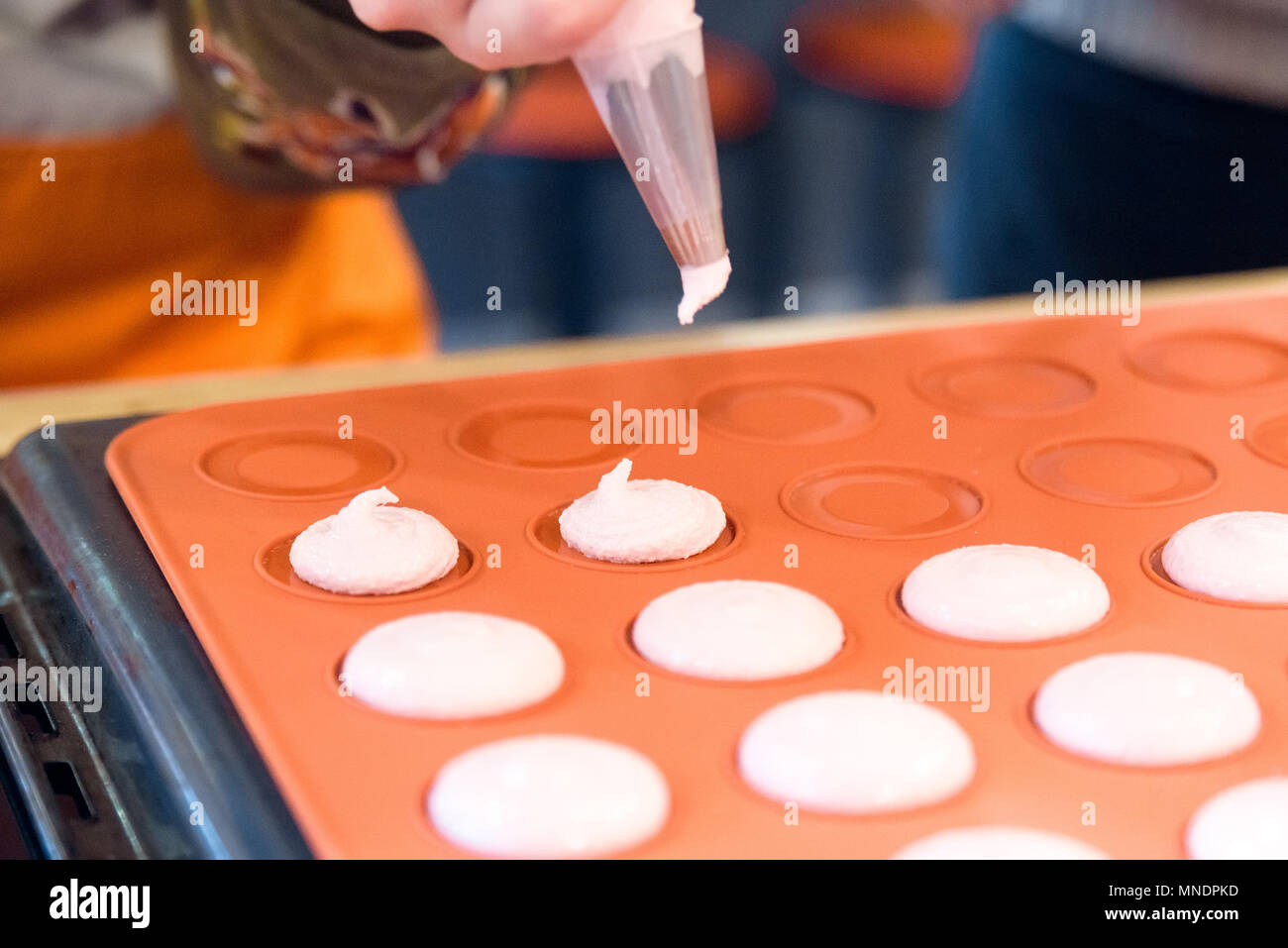 Koch mit Süßigkeiten Tasche quetschen Cremefüllung zu macarons Schalen in der Konditorei. Stockfoto