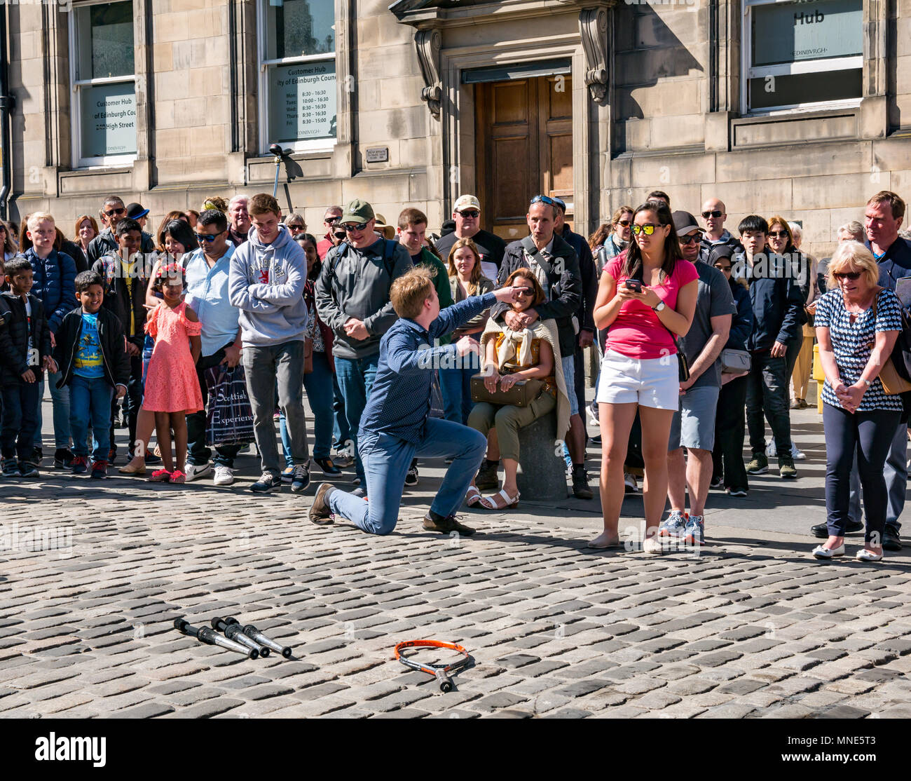Royal Mile, Edinburgh, 16. Mai 2018. Touristen, die Sonnenschein und Straßenunterhaltung auf der Royal Mile, Edinburgh, Schottland, Großbritannien genießen. Touristen beobachten einen Straßenkünstler namens Daniel, zu dessen Handlung das Jonglieren flammender Fackeln und großer Messer und Macheten gehört Stockfoto