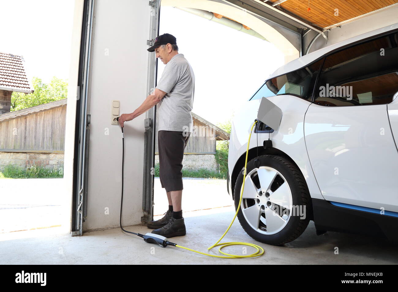 Ein Mann Laden Elektroauto am Auslass zu Hause Stockfoto