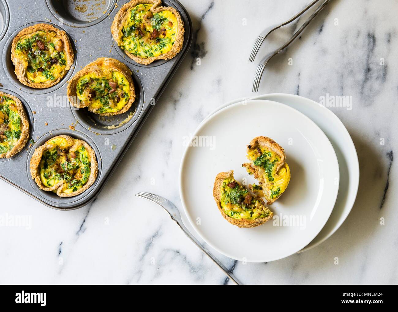 Mini quiches mit Zucchini, Speck und Petersilie in einem Muffin tin Stockfoto
