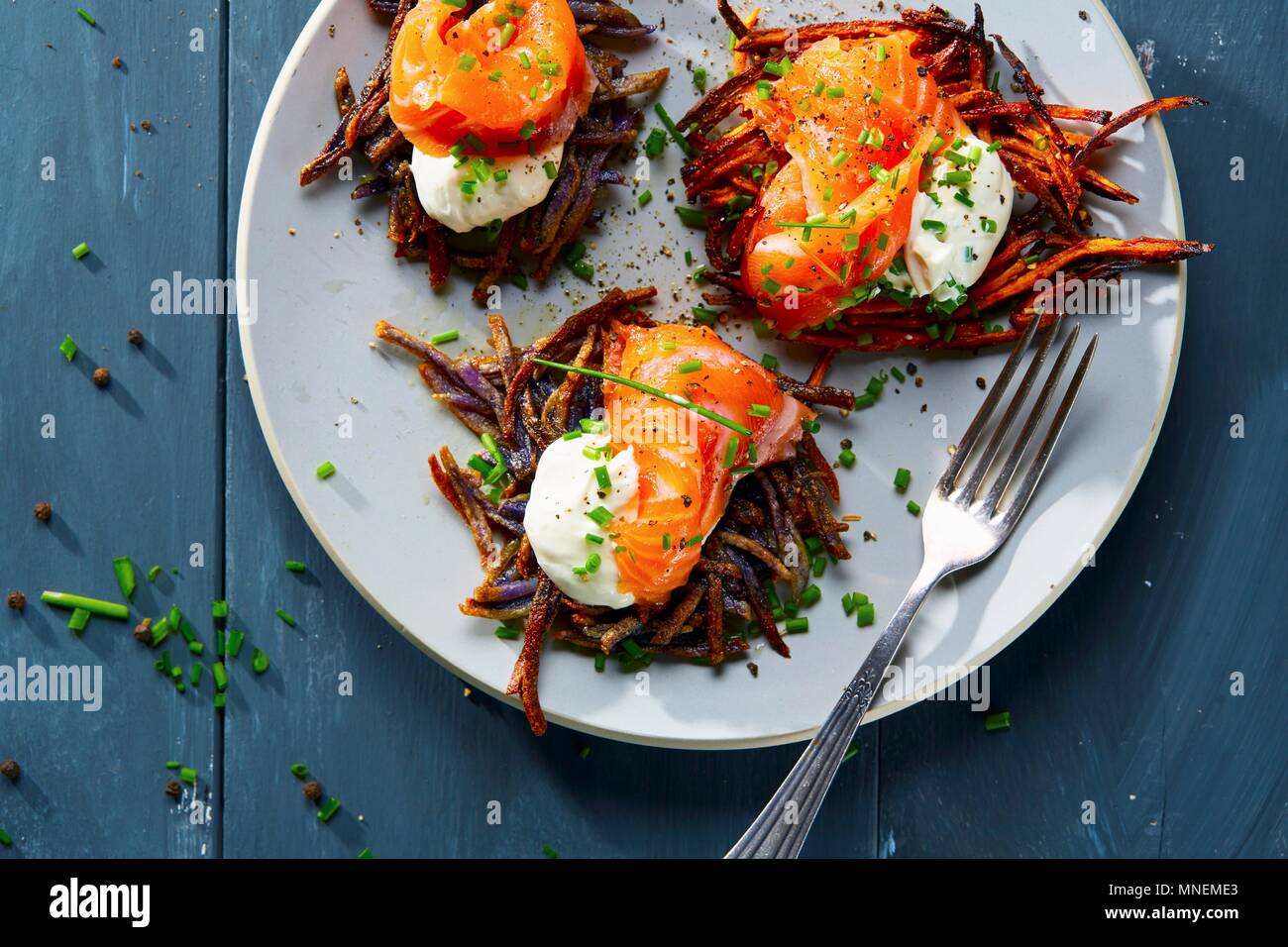 Vitelotte Rösti (gebratene Schweizer Kartoffel Kuchen) mit Crème fraîche und Lachs Stockfoto