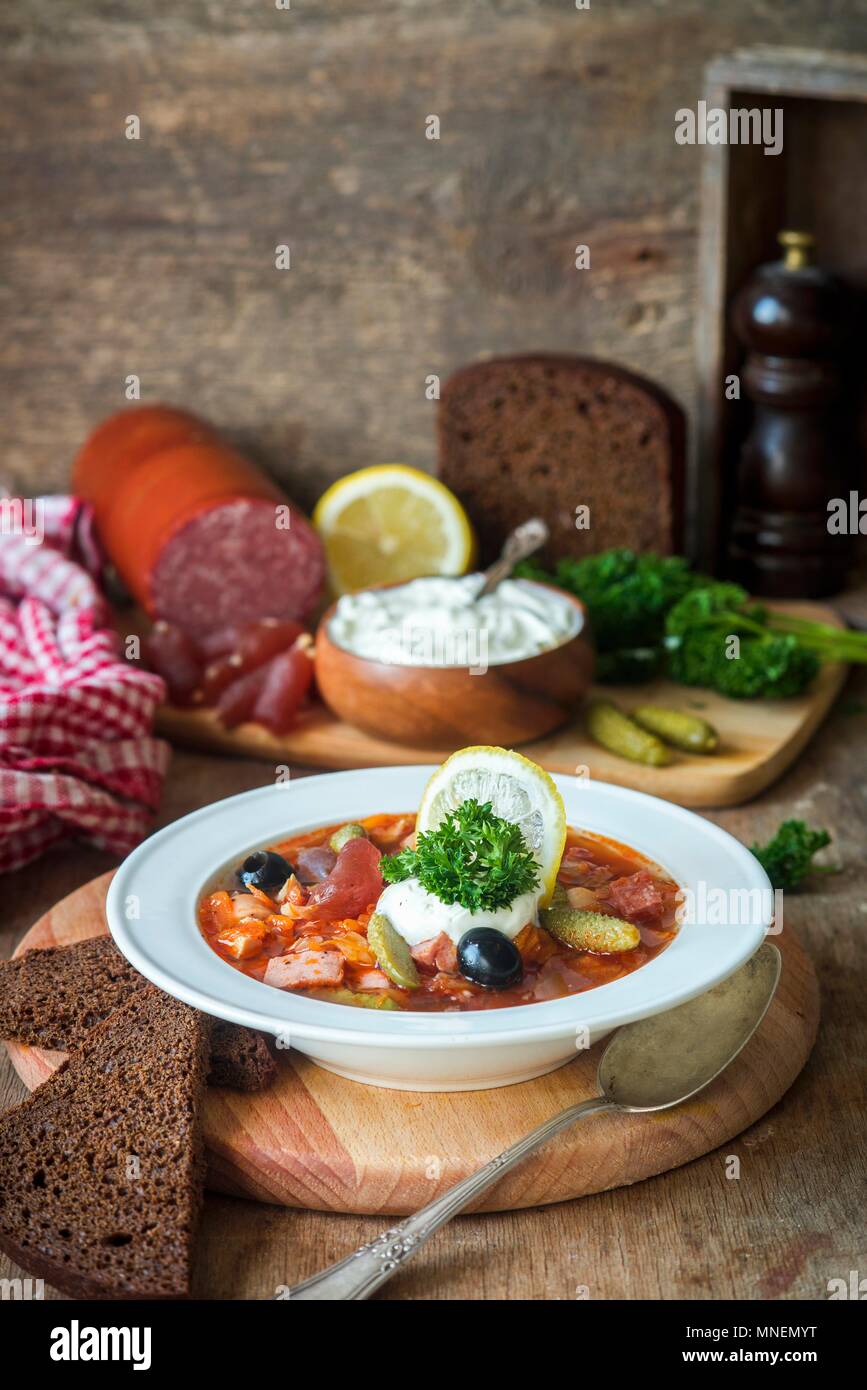 Solyanka (traditionelle russische Fleischsuppe aus verschiedenen Arten von Fleisch und Würstchen mit Gurken und Zitrone) Stockfoto