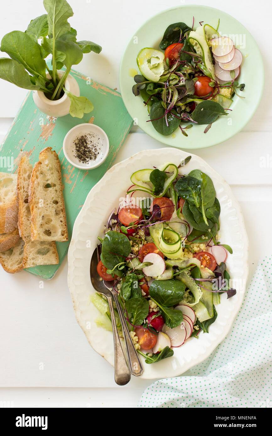 Spinat Salat mit Radieschen, Gurken, rote Beete Blätter, Cherry Tomaten, Quinoa, Brot und schwarzer Pfeffer Stockfoto