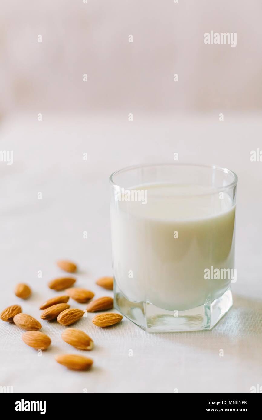 Ein Glas Milch und Mandeln auf einem weißen Tischtuch Stockfoto