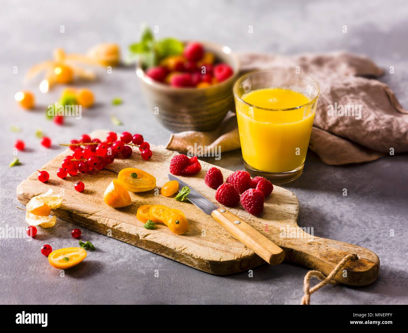 Frisches Obst auf einem Schneidebrett und ein Glas Saft Stockfoto
