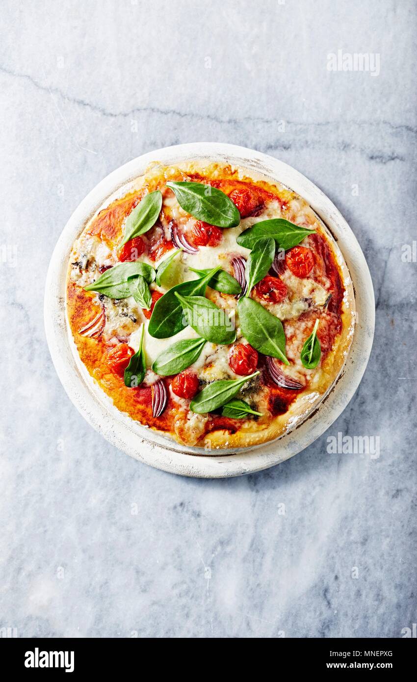 Pizza mit Mozzarella und gorgonzolla gekrönt mit Spinatblättern Stockfoto