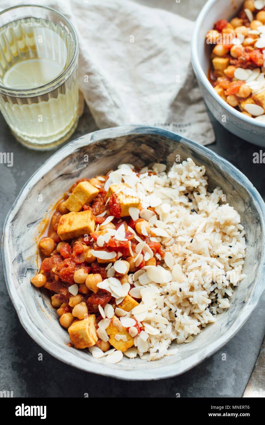 Vegan mit Kichererbsen und Tofu Curry, serviert mit braunem Reis und Mandelflocken Stockfoto