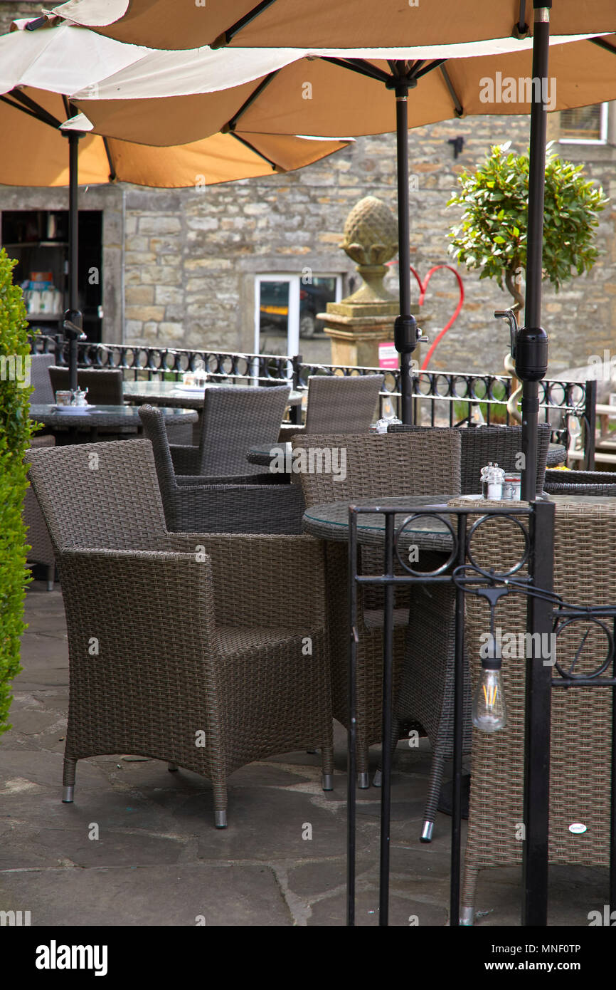 Außerhalb essen und trinken mit Korbsesseln und Tischen und Sonnenschirmen außerhalb Hotel in Grassington. Nr Skipton, North Yorkshire Stockfoto