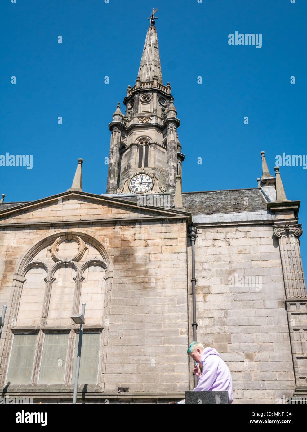 Junger Mann außerhalb Tron Kirk, Jäger Platz sitzen, mit Hilfe einer E-Zigarette mit Turm gegen den blauen Himmel, Edinburgh, Schottland, Großbritannien Stockfoto