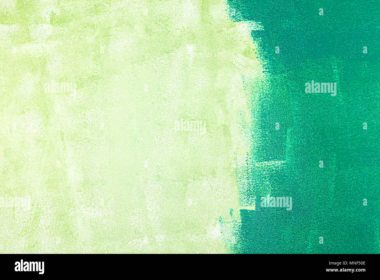 Unvollendete bemalte Wand mit grüner Farbe durch Farbroller Stockfoto