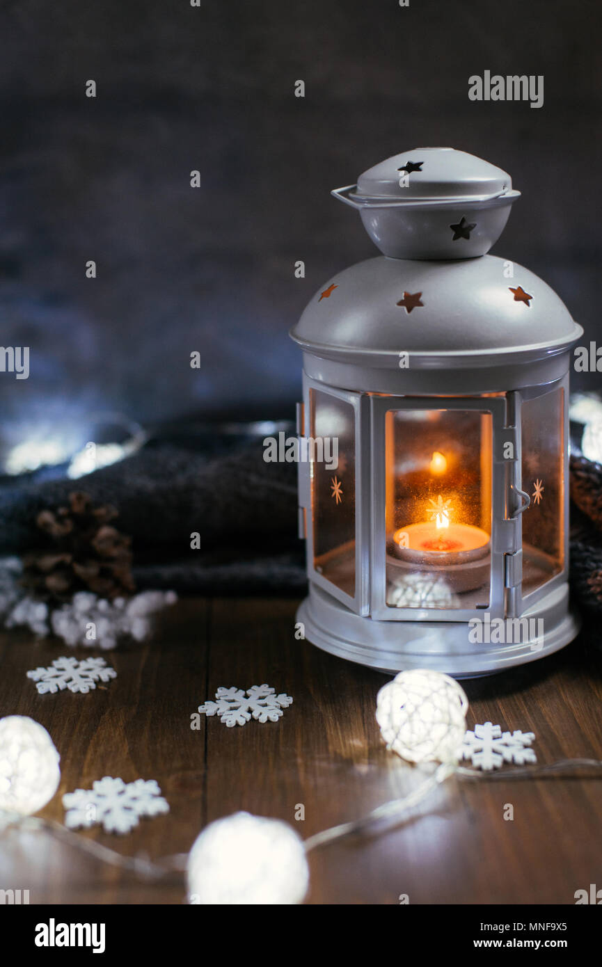 Gemütliche winter home. Eine Laterne, eine Kerze, eine Girlande,  Schneeflocken, ein Kegel, ein gestricktes graue Strickjacke auf einem  Holztisch. Die Atmosphäre der Märchen ist ein Neues Jahr t Stockfotografie  - Alamy