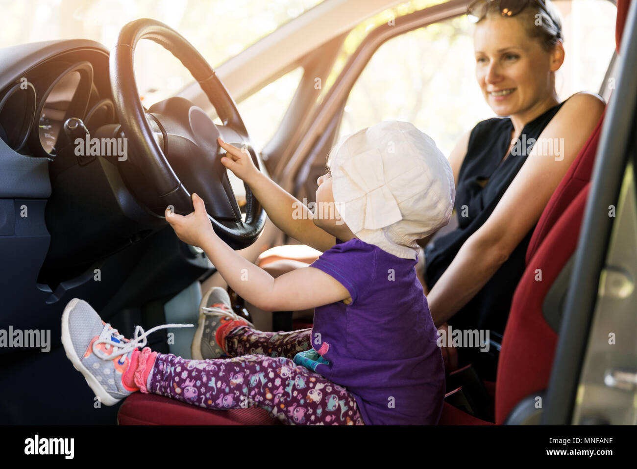 Mutter mit Kind spielen im Auto Lenkrad Stockfoto