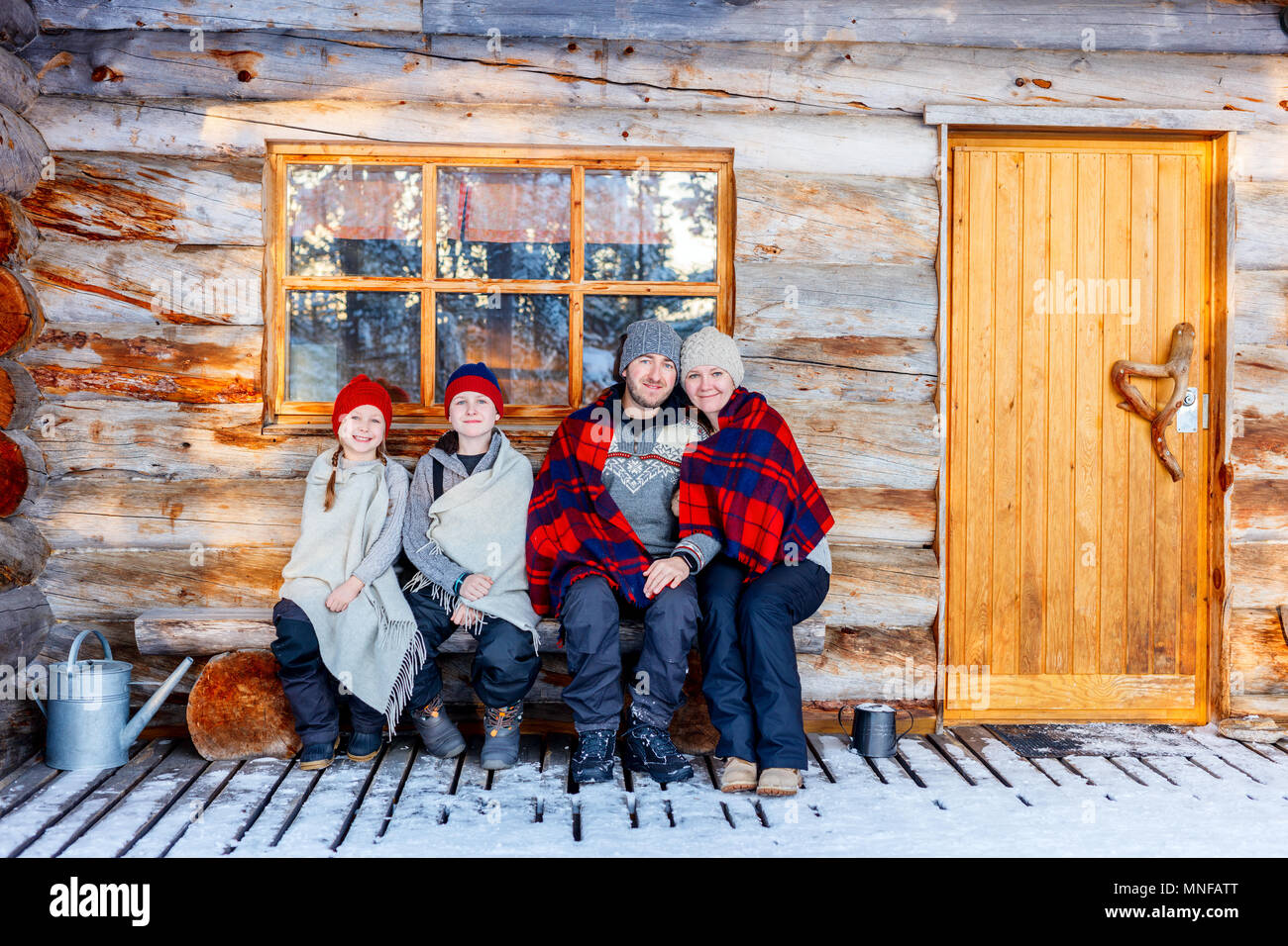 Familie mit Kindern im Freien auf der schönen Wintertag vor der Hütte Ferienhaus anmelden Stockfoto