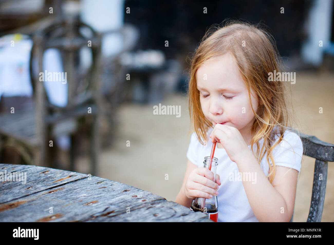 Adorable kleine Mädchen trinken mit dem Strohhalm ein alkoholfreies Getränk Stockfoto