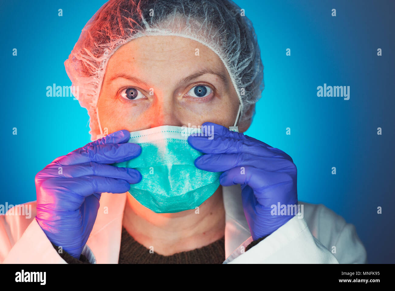 Weibliche Chirurg setzt auf schützende chirurgische Maske vor der Operation Operation im Krankenhaus Klinik Op Stockfoto