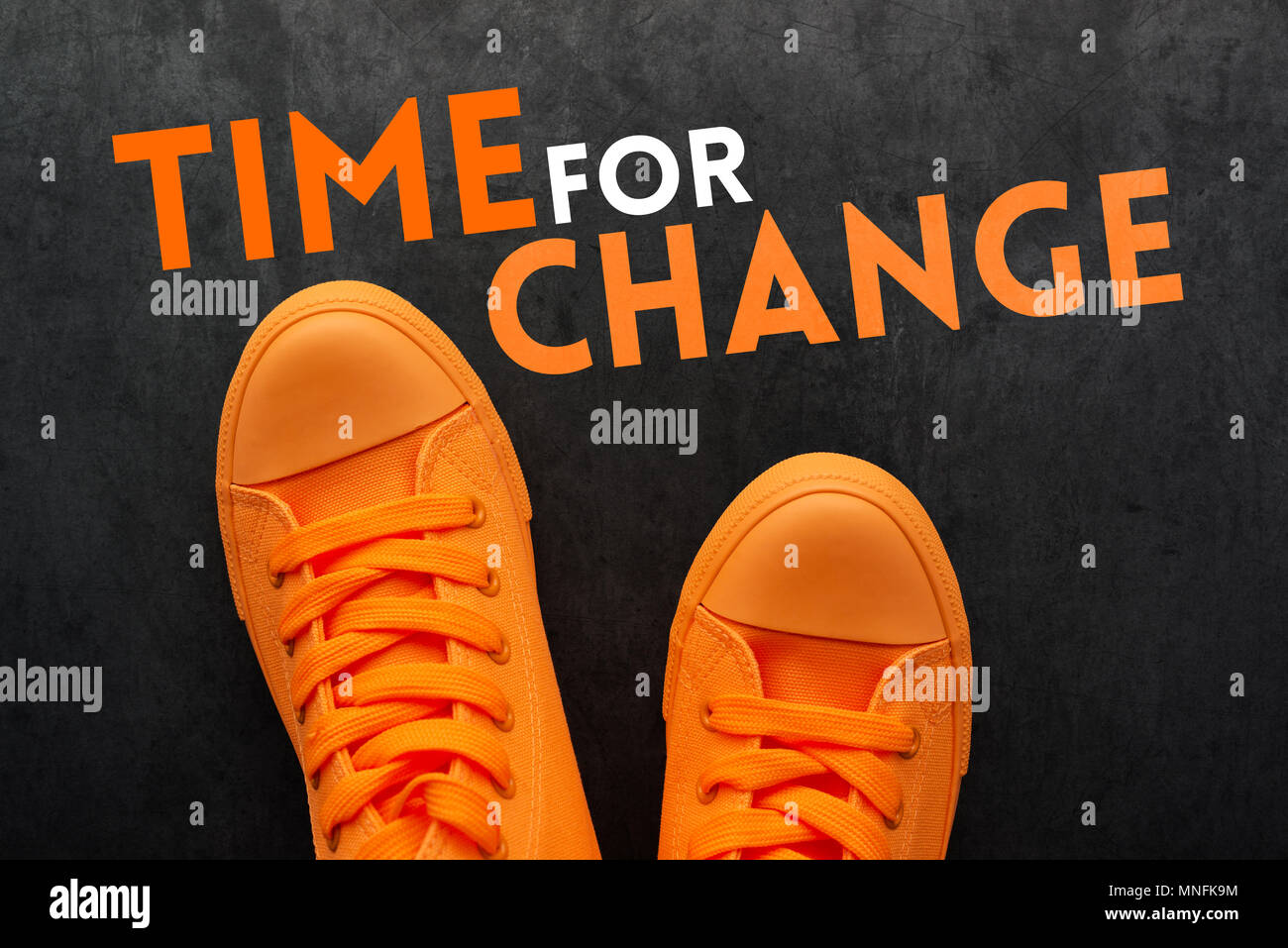 Zeit für Veränderungen, junge Person, die Entscheidung über die Wahl der alternative Pfad im Leben, Blick von oben auf die orange Sneakers auf Betondecke mit Motiv Stockfoto