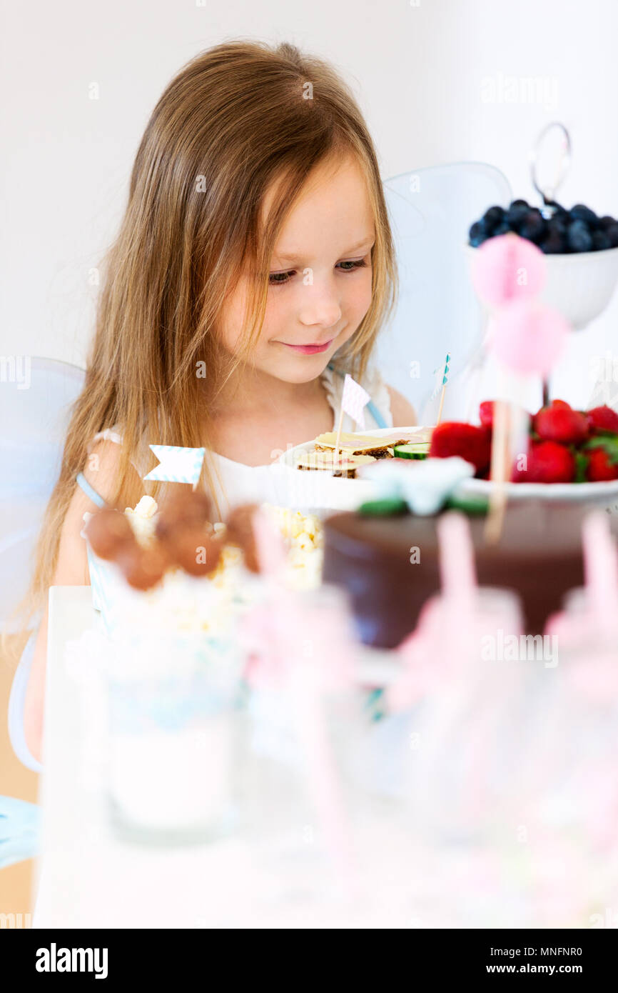 Adorable kleine Fee Mädchen auf einer Geburtstagsfeier vor Dessert Tabelle Stockfoto