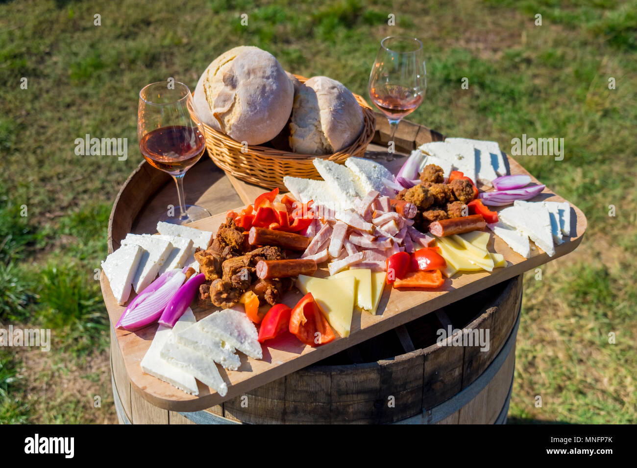 Erntesaison traditionelle rumänische Küche Teller mit Käse, Brot, Wurst, Zwiebeln und roter Wein im Glas in Weinbergen Stockfoto