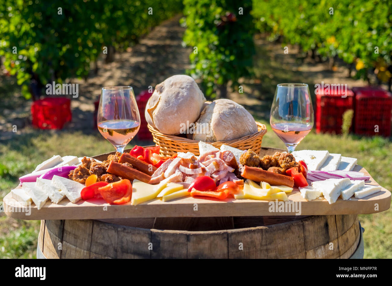 Erntesaison traditionelle rumänische Küche Teller mit Käse, Brot, Wurst, Zwiebeln und roter Wein im Glas in Weinbergen Stockfoto